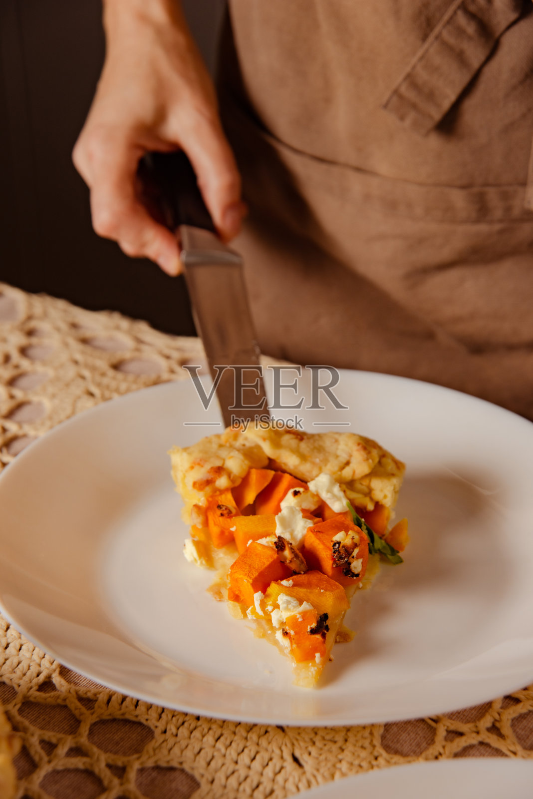 特写:女人的手把美味的馅饼——素食南瓜馅饼放在白色盘子里照片摄影图片