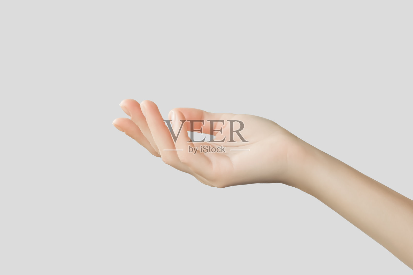 女性的手拿着灰色背景上看不见的东西照片摄影图片