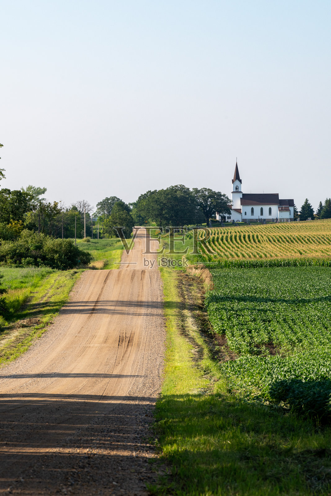 在一个阳光明媚的日子里，俯视着一条两旁是田野和教堂的乡村道路。照片摄影图片
