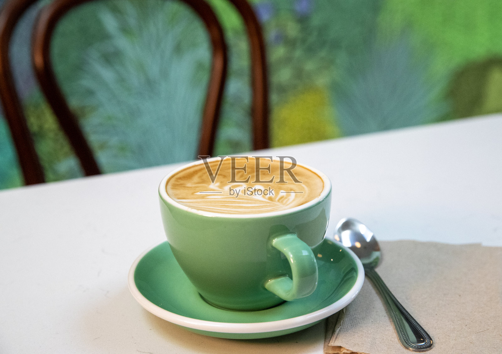 一杯颜色一致的咖啡，一把勺子，一把空椅子照片摄影图片