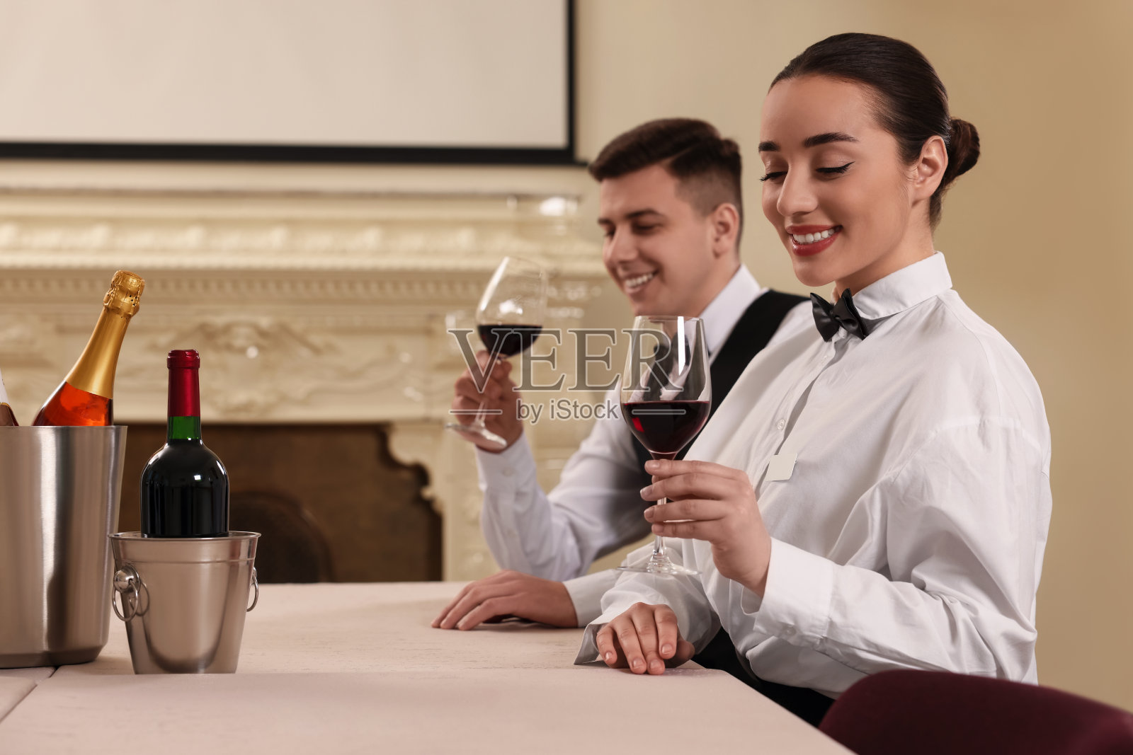 一群人在室内的餐桌上用玻璃杯品尝红酒。专业管家课程照片摄影图片