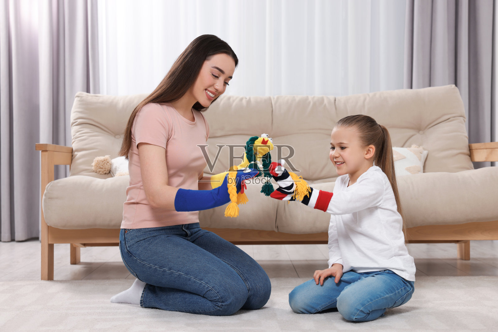 快乐的母亲和女儿在家里一起玩有趣的袜子木偶照片摄影图片