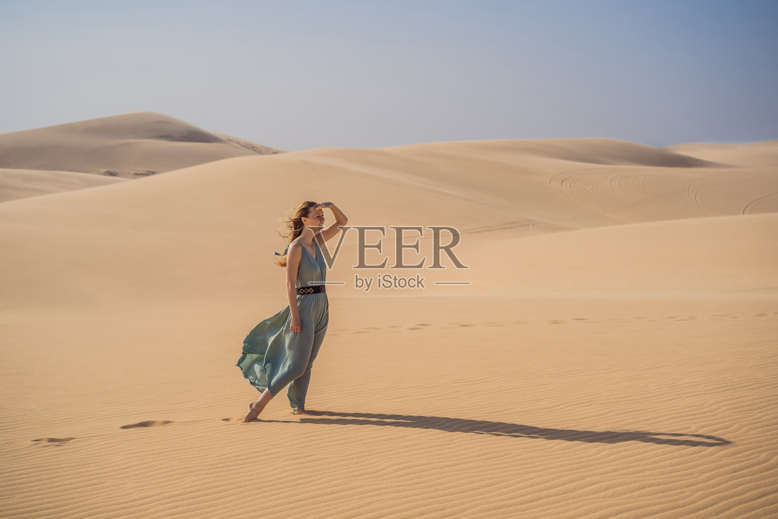 年轻美丽的女人在沙漠中旅行。阳光明媚的夏日，沙丘和蓝天。旅行、冒险、自由的理念。旅游业在COVID - 19隔离后重新开放照片摄影图片
