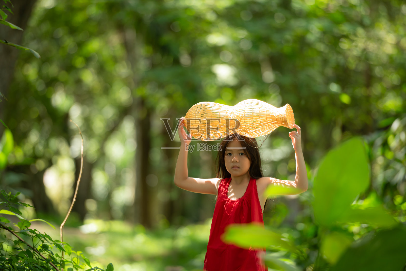穿着红色衣服的亚洲小女孩在森林里拿着渔具，泰国农村生活的生活理念照片摄影图片