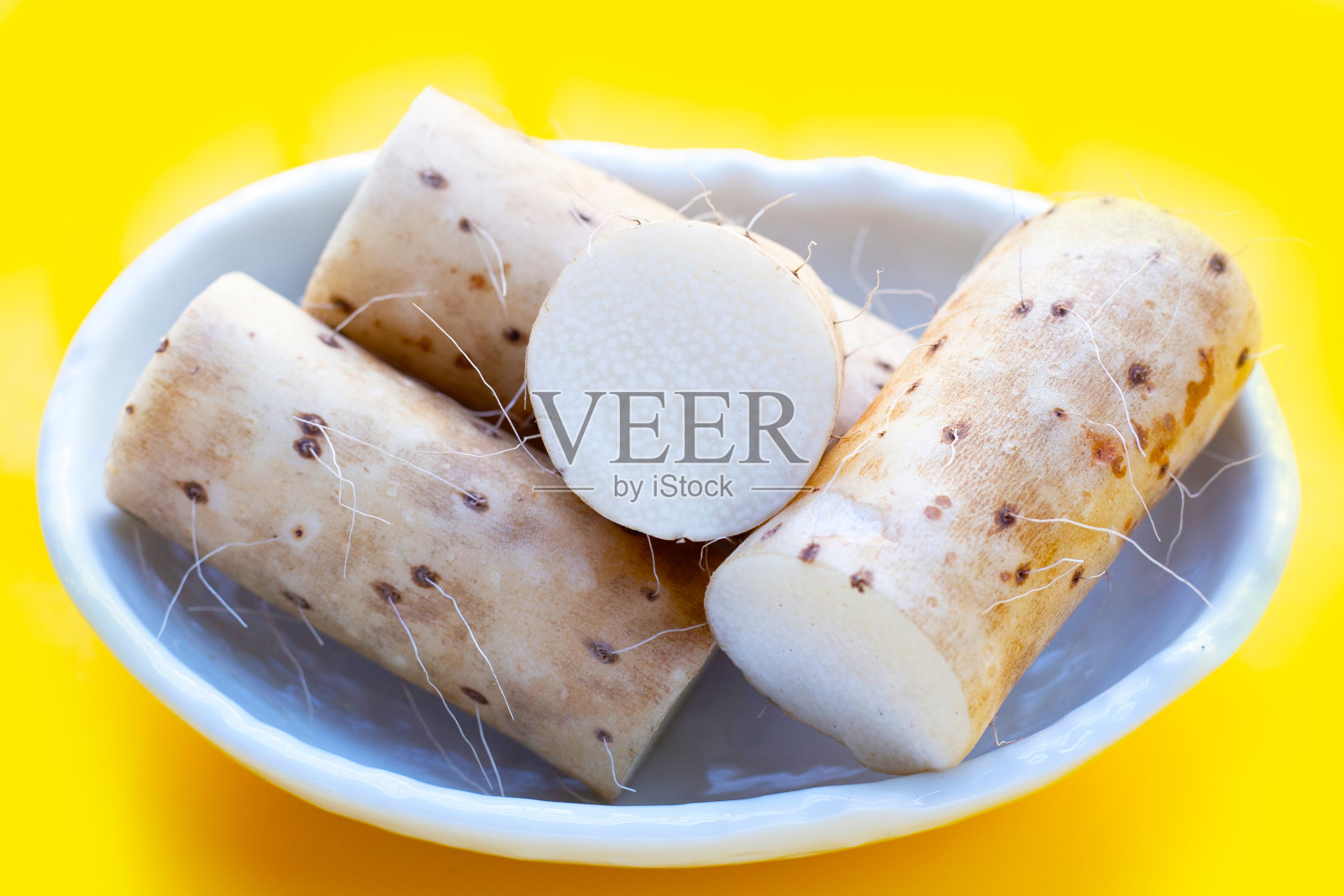 黄色背景上新鲜的nagaimo。照片摄影图片