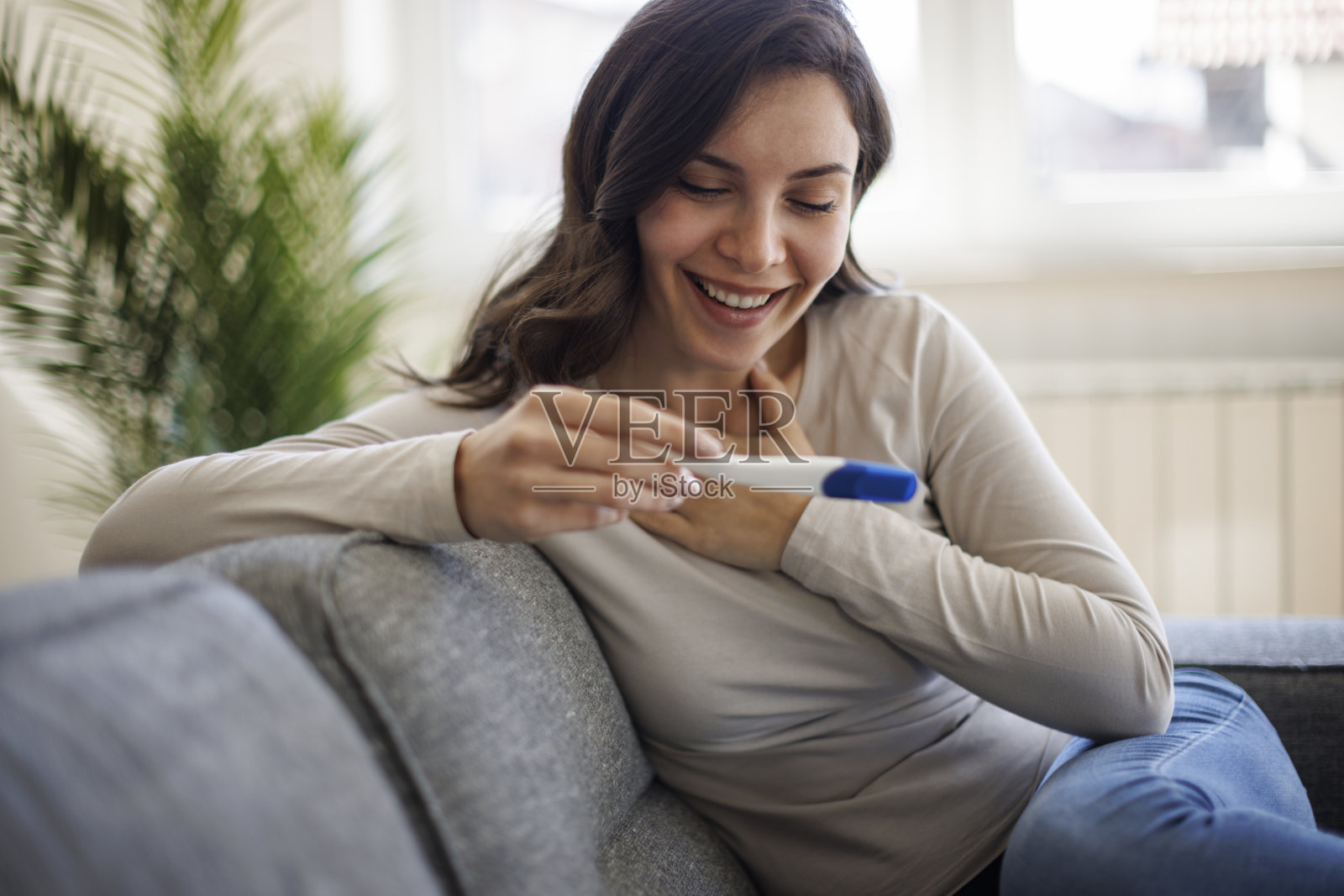 兴奋快乐的女人看着验孕棒照片摄影图片