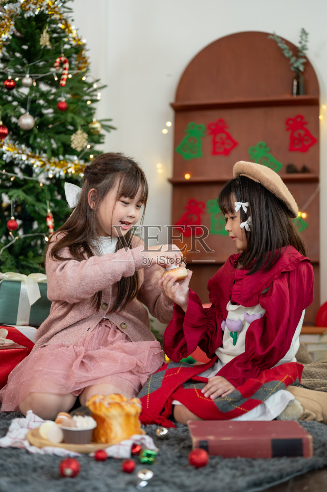 两个可爱又快乐的亚洲小女孩在客厅里一起享受着吃糖果的乐趣。照片摄影图片