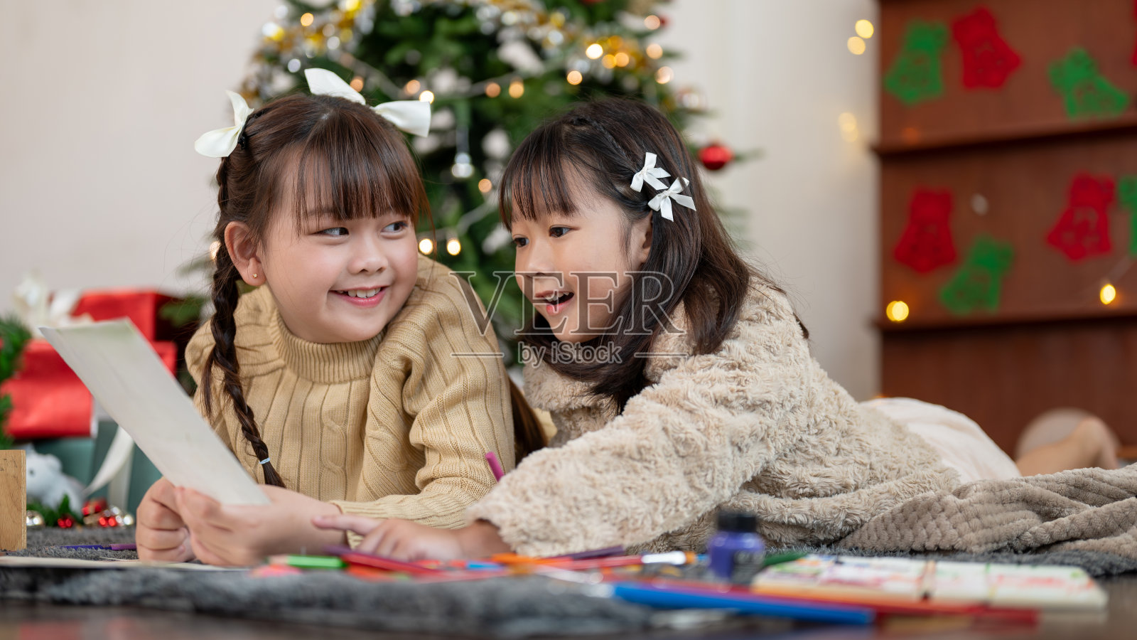 两个可爱的年轻亚洲女孩在一起玩得很开心，喜欢聊天和制作圣诞贺卡。照片摄影图片