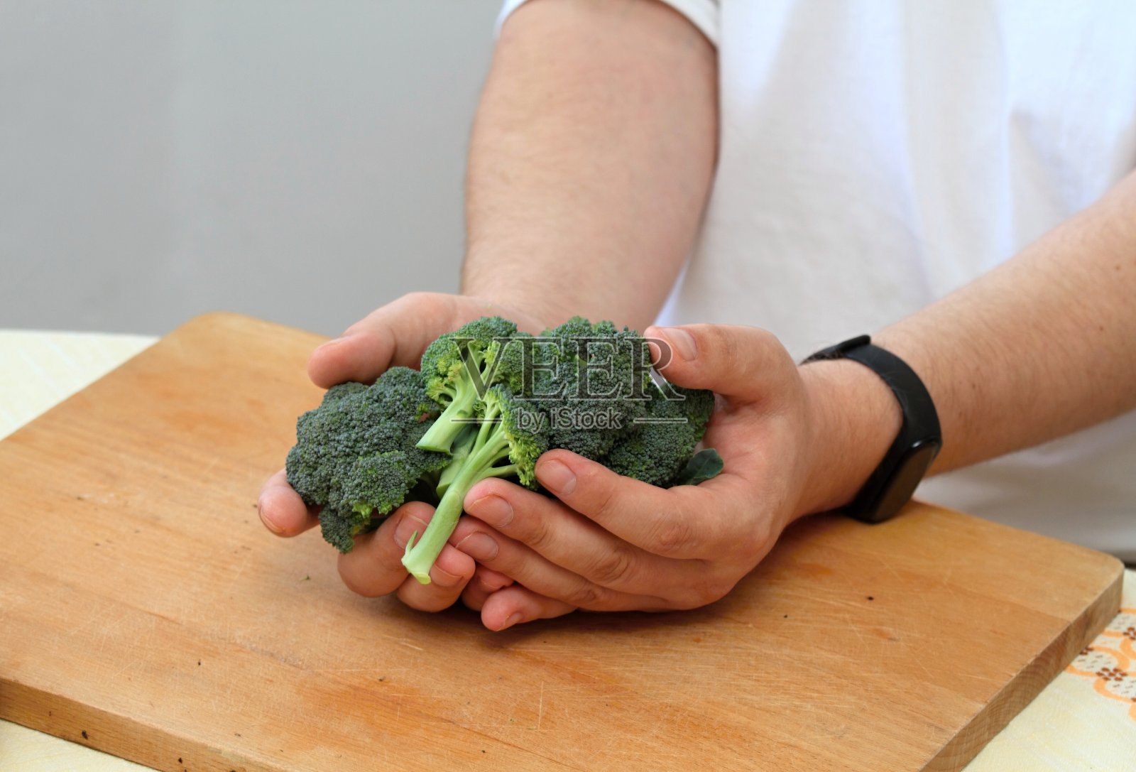 男人的手拿着新鲜的生西兰花。照片摄影图片