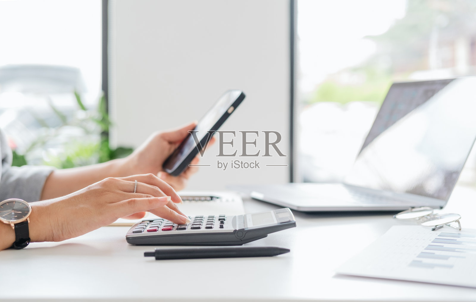 近距离的年轻女性正在做财务文书工作，规划投资，计算国内支出，税收，水电费，检查移动电子银行应用程序中的数据或在线支付服务。照片摄影图片