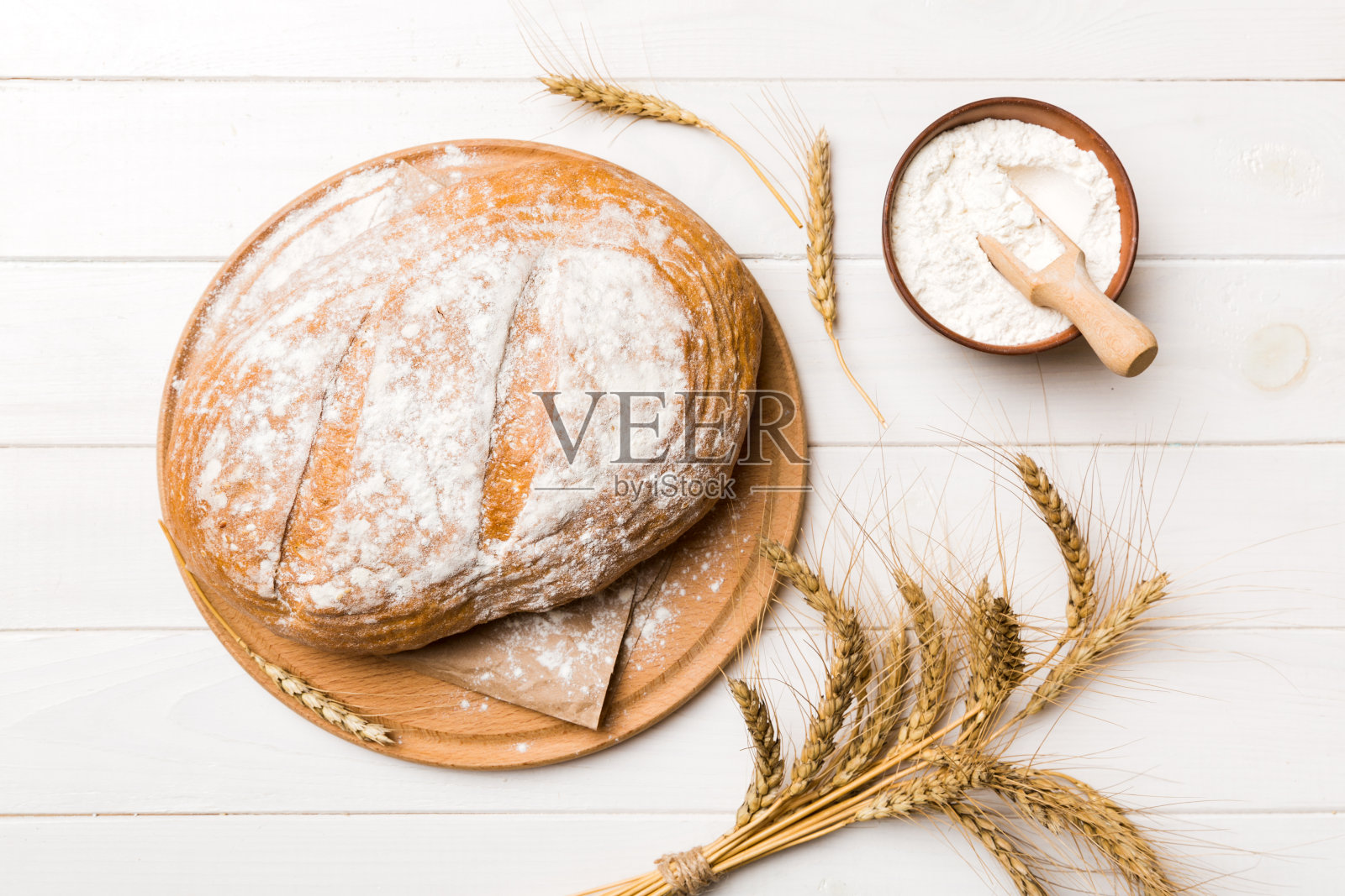 刚烤好的面包放在砧板上，白色的木制背景。顶部视图面包与复制空间照片摄影图片