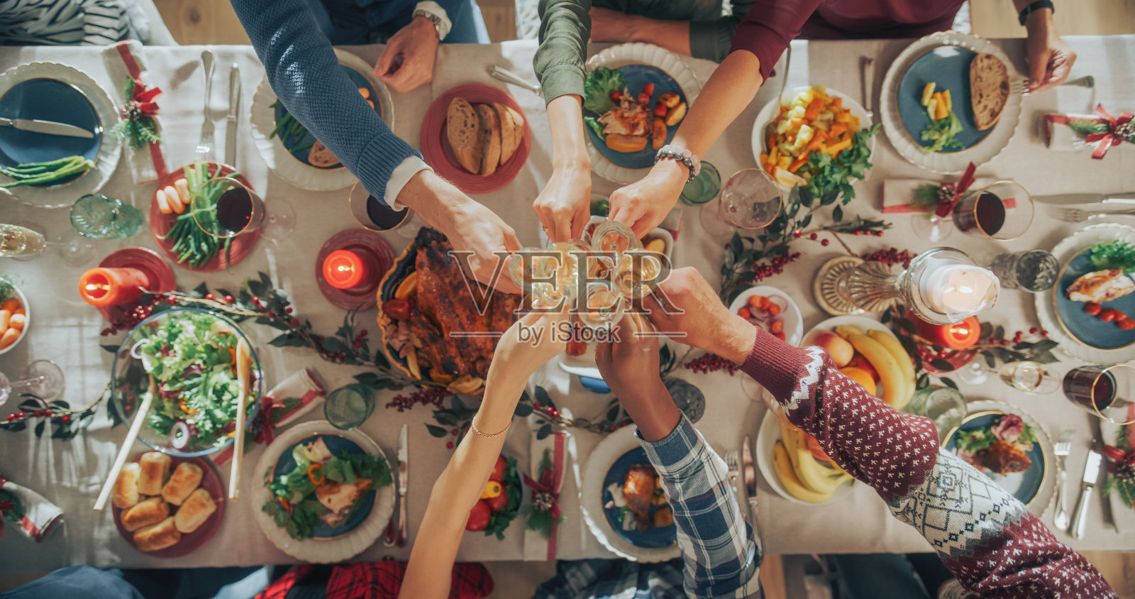 家人和朋友聚在家里吃传统的圣诞晚餐，烤火鸡盛宴。从上往下看，人们举起香槟酒杯举杯，一起庆祝节日照片摄影图片