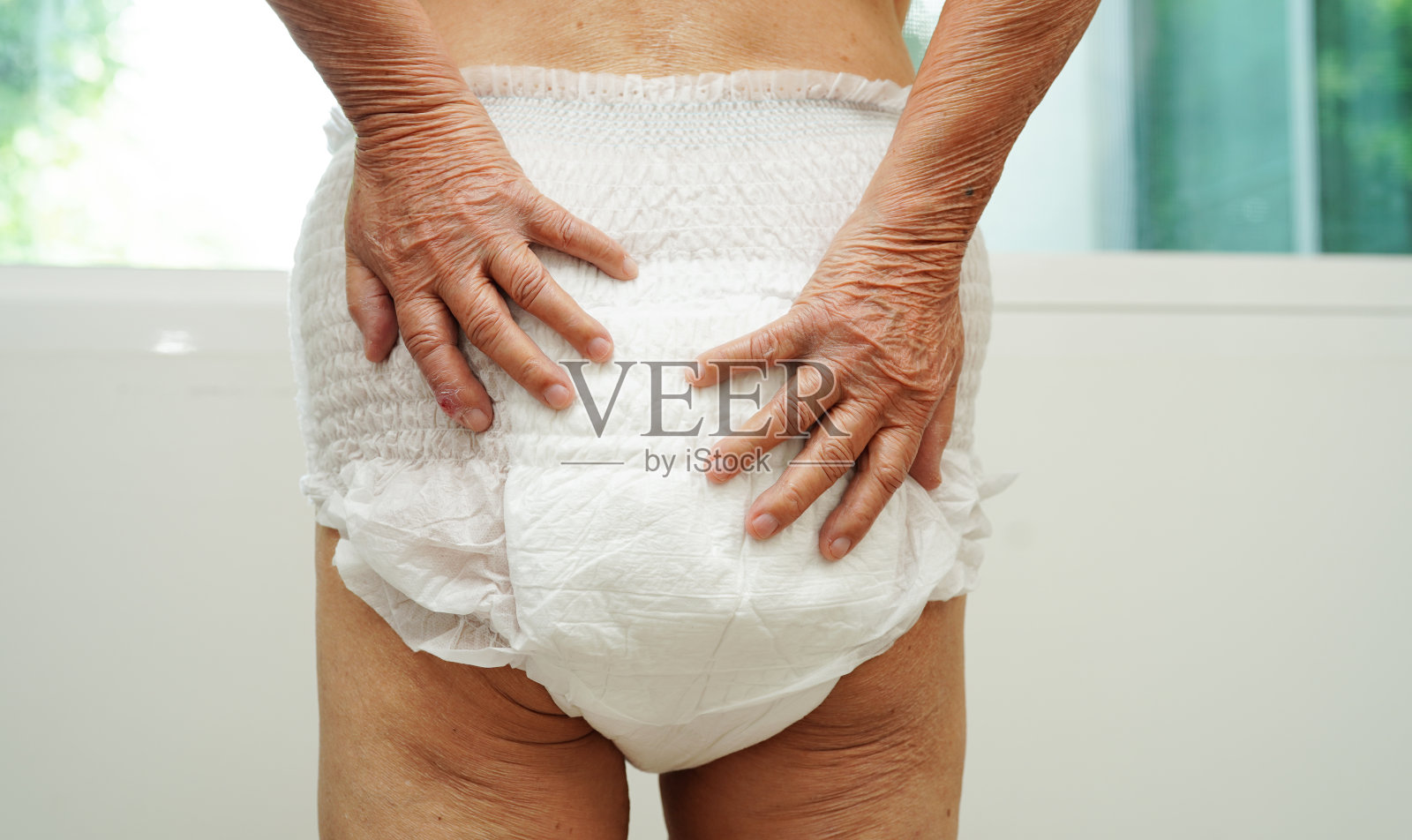 亚洲老年女性患者在医院使用成人尿失禁尿布垫。照片摄影图片