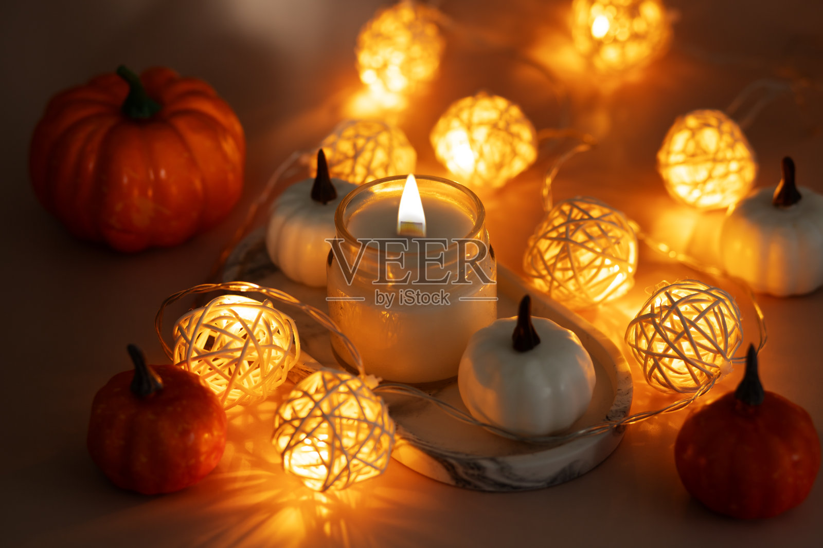 芳香燃烧的蜡烛在大理石托盘与南瓜和温暖的灯，舒适的极简主义设计，芳香疗法，水疗放松照片摄影图片