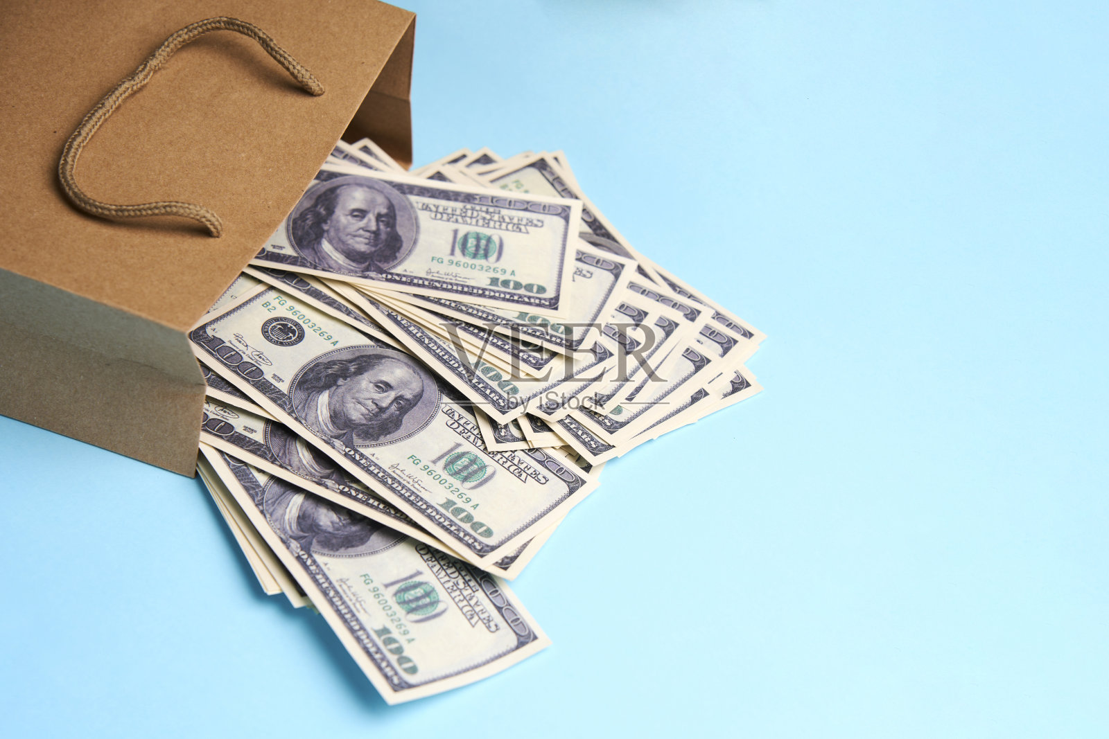 装有美元纸币的纸袋，蓝色背景照片摄影图片