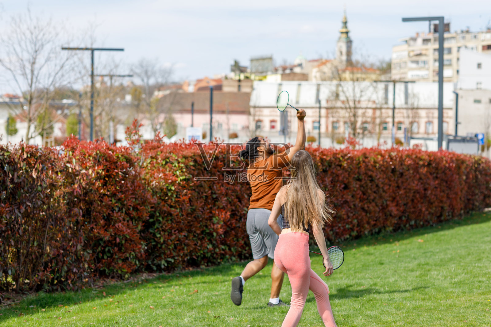 快乐的多种族夫妇在公园里玩羽毛球。照片摄影图片