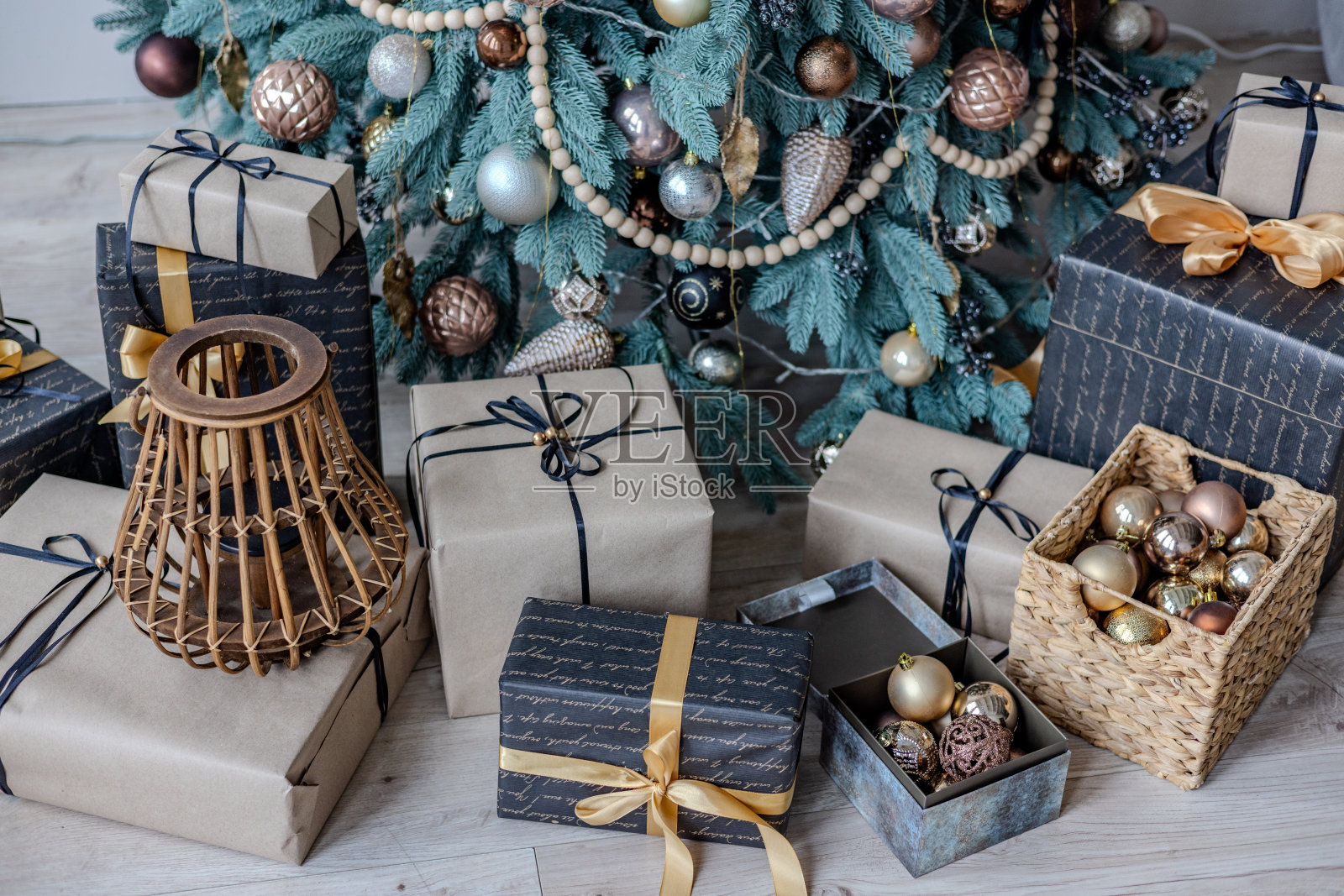 各种各样的彩色圣诞礼物站在装饰圣诞树附近的房子在地板上的树枝下照片摄影图片