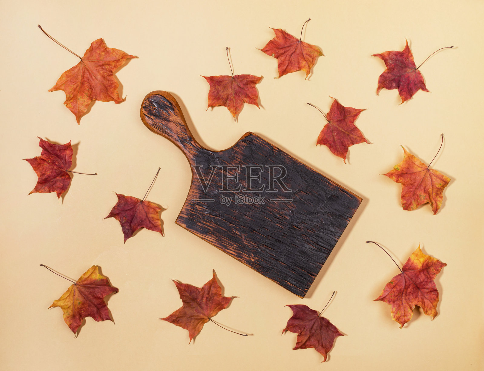 枫树叶的排列，中间是中性浅米色的空木板。照片摄影图片