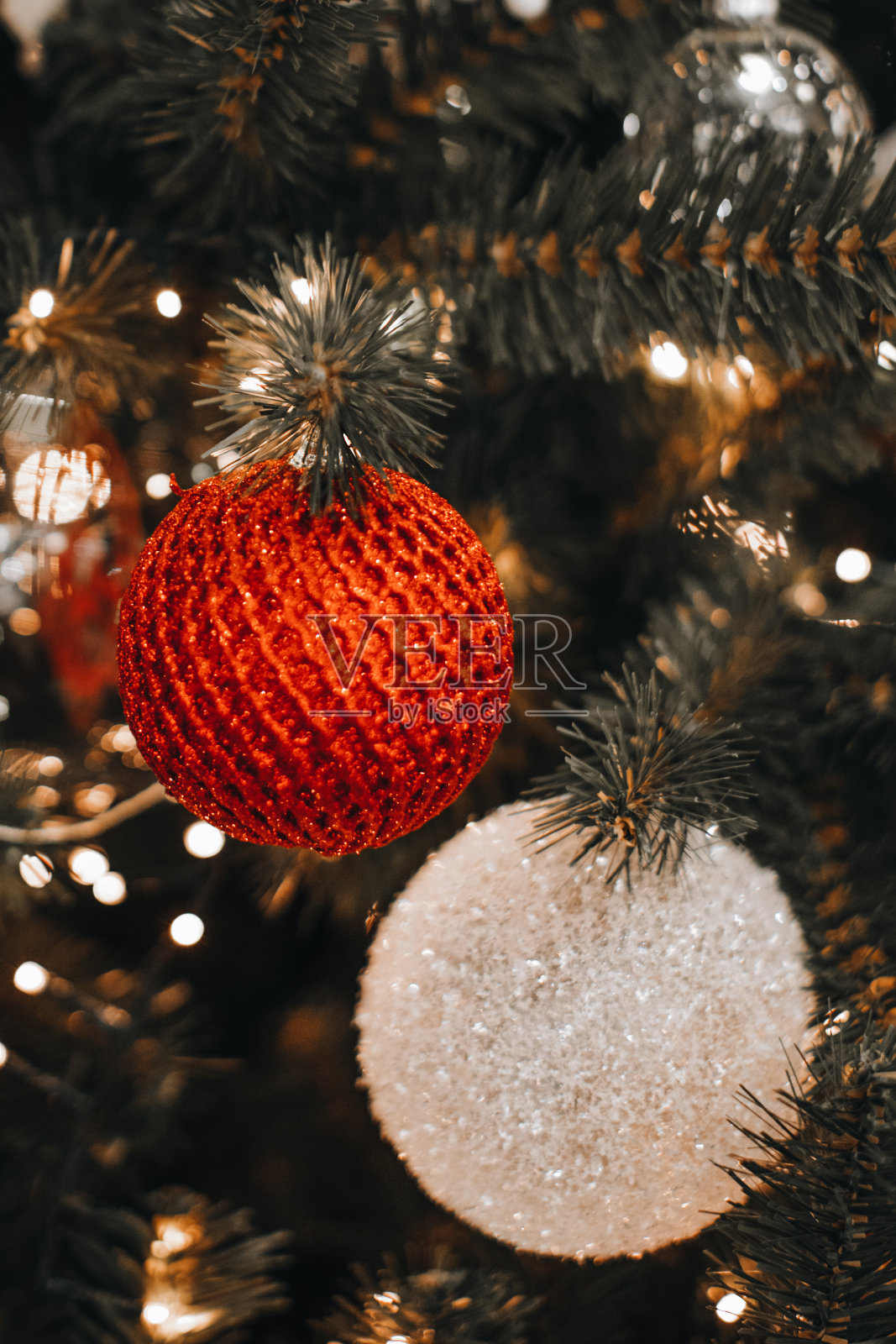 银白色和红色闪闪发光的圣诞球挂在圣诞树上。照片摄影图片