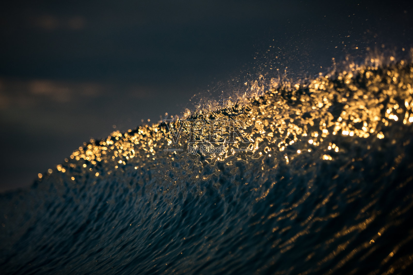 在丰富的金色光线下，波浪破碎的纹理面照片摄影图片