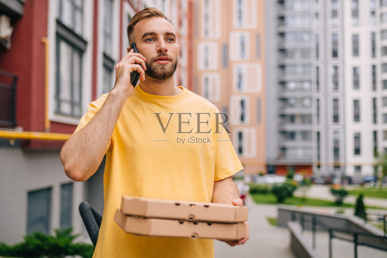 辛勤工作的快递员拿着一个盒子在打电话。安全邮递货物。照片摄影图片