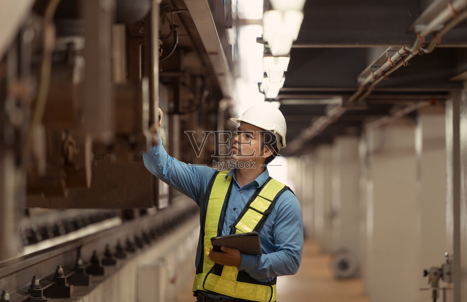 电动列车停放在电动列车修理厂后，电动列车工程师按检查轮用平板对电动列车机械进行检查照片摄影图片