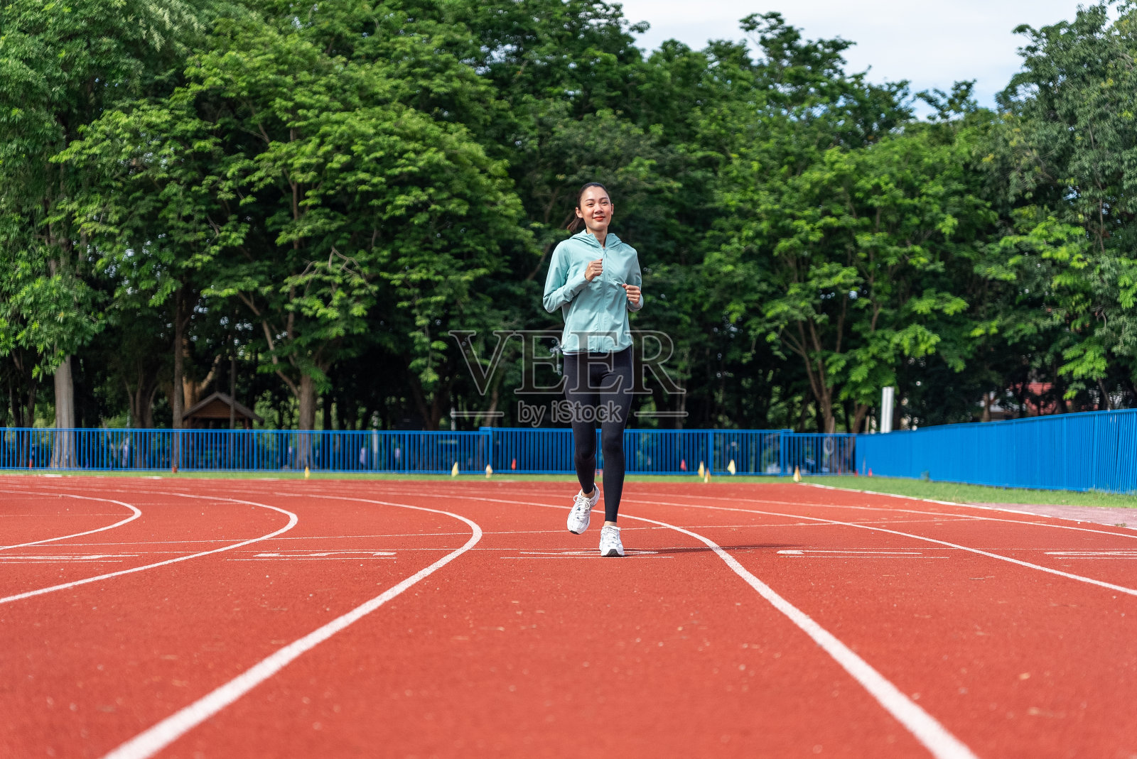 年轻的亚洲女性在早晨进行有跑道背景的户外跑步锻炼。概念健康跑步和户外运动，跟踪拍摄。照片摄影图片