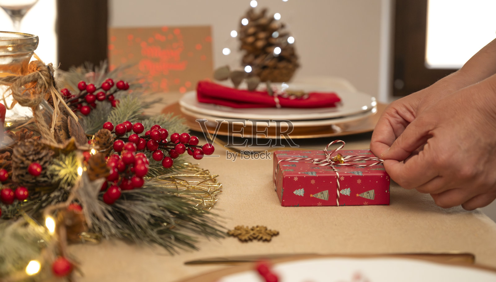 一个无法辨认的女人将礼物放在圣诞桌上的手的特写。照片摄影图片