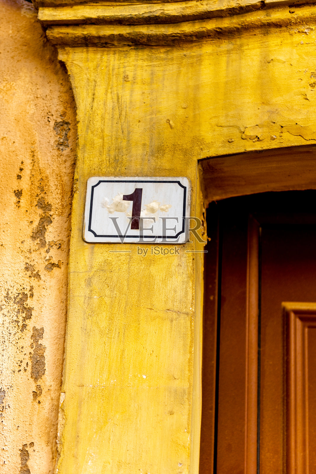 入口处一幢黄漆老房子的墙上写着门牌号。克里特岛,希腊。照片摄影图片