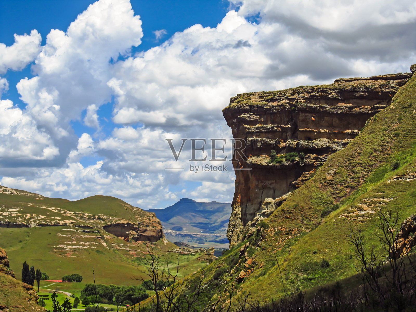 在南非的金门高地国家公园里，巨大的砂岩扶壁，名为Brandwag，映衬着晴朗的天空和积云。照片摄影图片