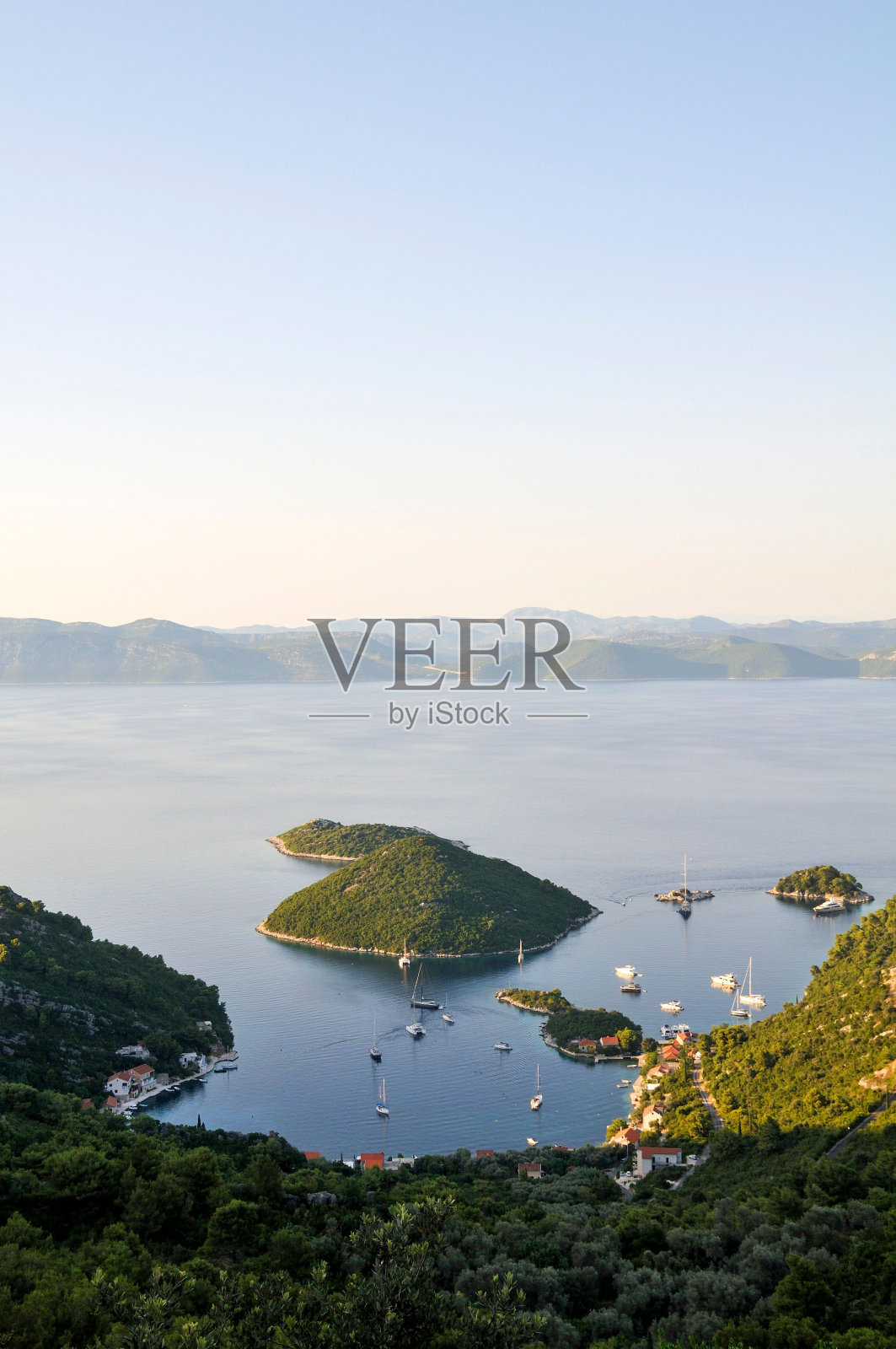 风景如画的岛屿坐落在一个宁静的水体中间:克罗地亚的米列特岛照片摄影图片