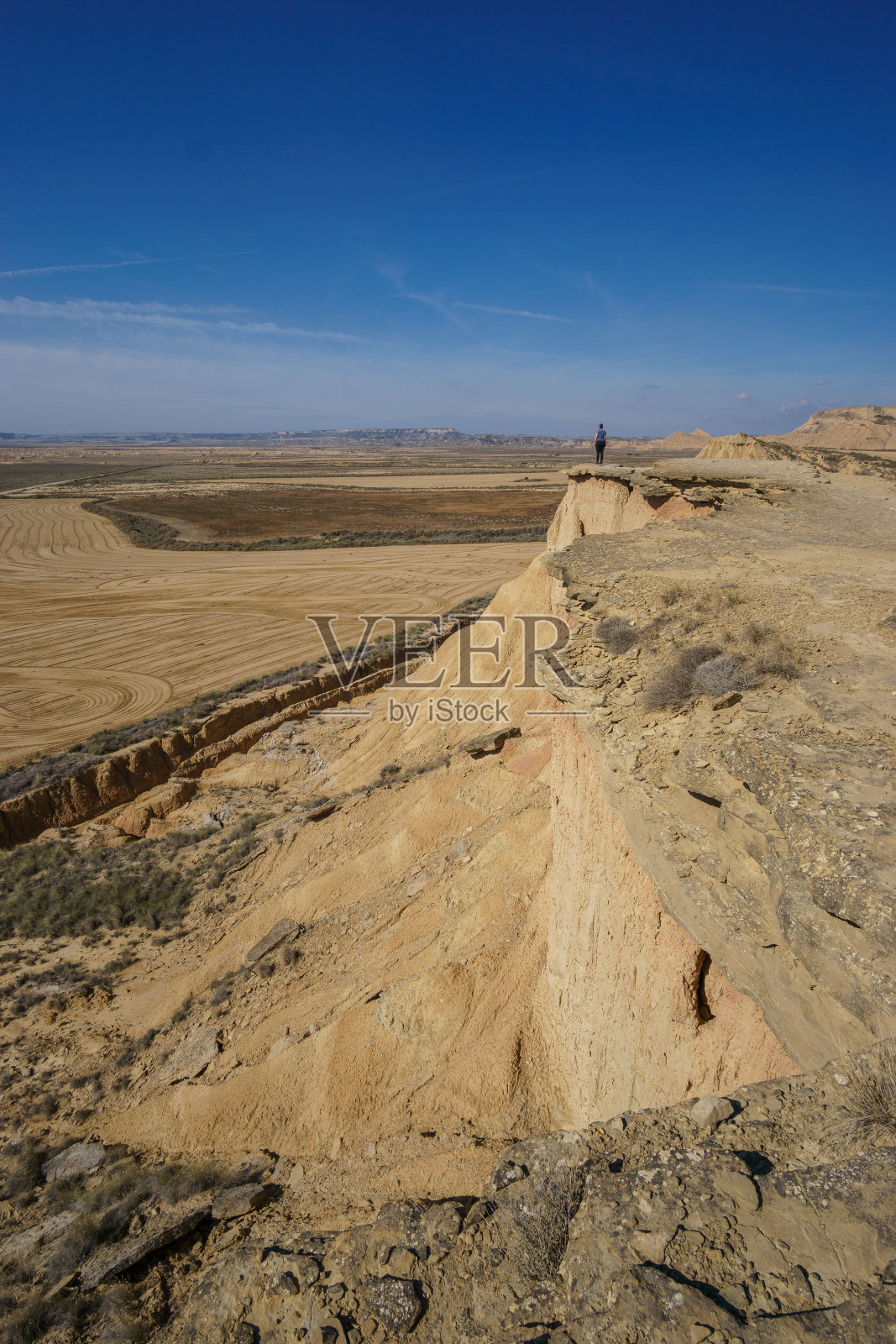 在西班牙纳瓦拉省阿格达斯，徒步旅行者在米拉多·德·胡安·奥比斯波欣赏巴迪纳斯·雷亚尔斯干旱高原的沙漠景观照片摄影图片