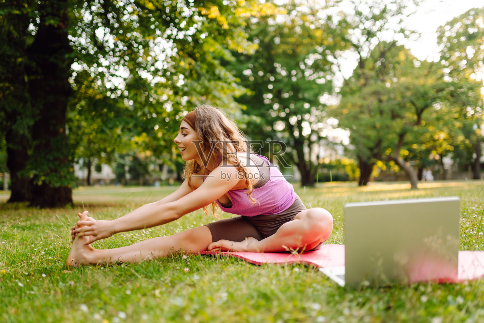 穿着运动服练习健身的快乐女人，用笔记本电脑上网上课。照片摄影图片