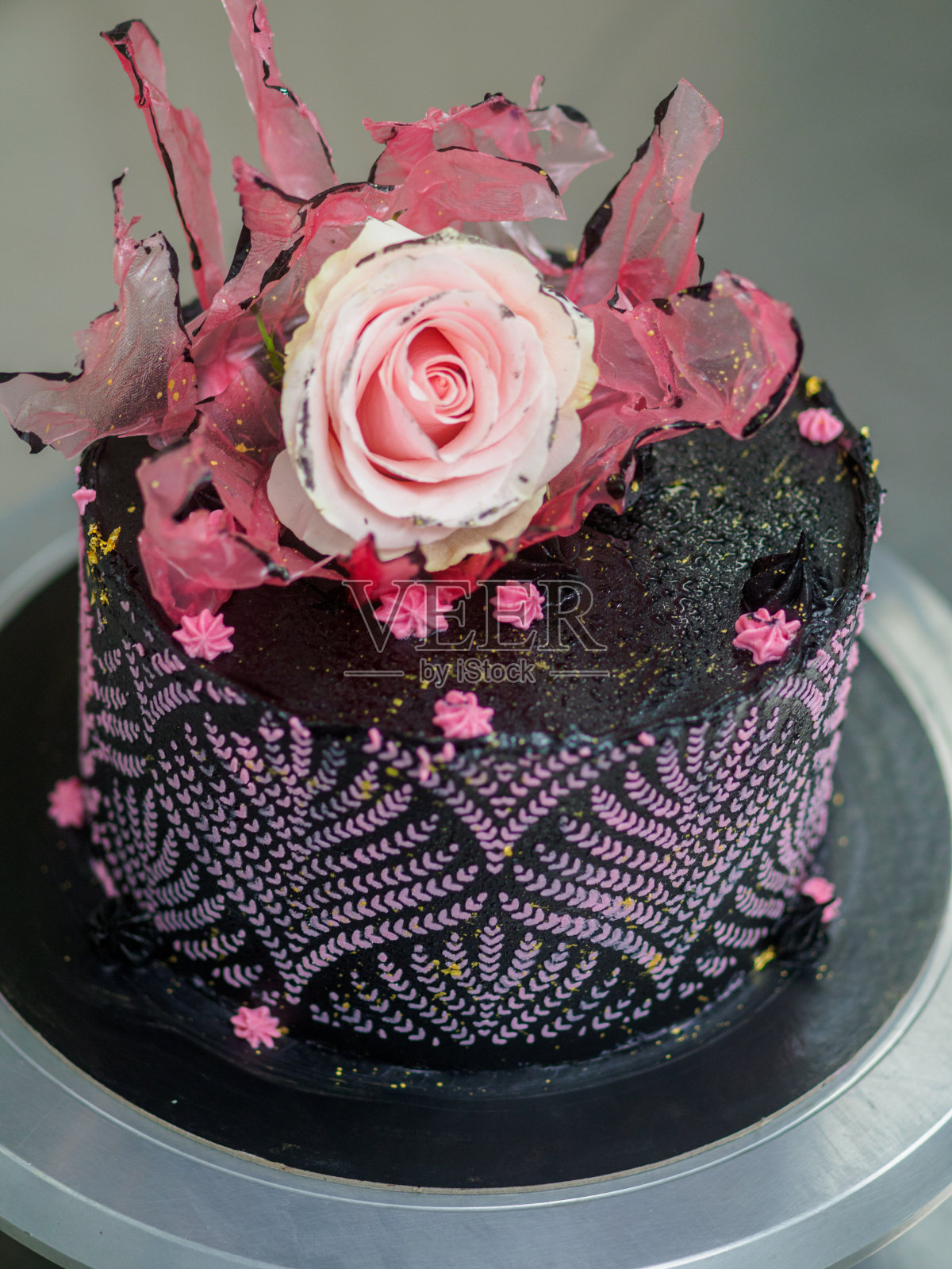 黑色的糖霜装饰生日蛋糕，真正的玫瑰装饰和粉红色的甜蜜漩涡照片摄影图片