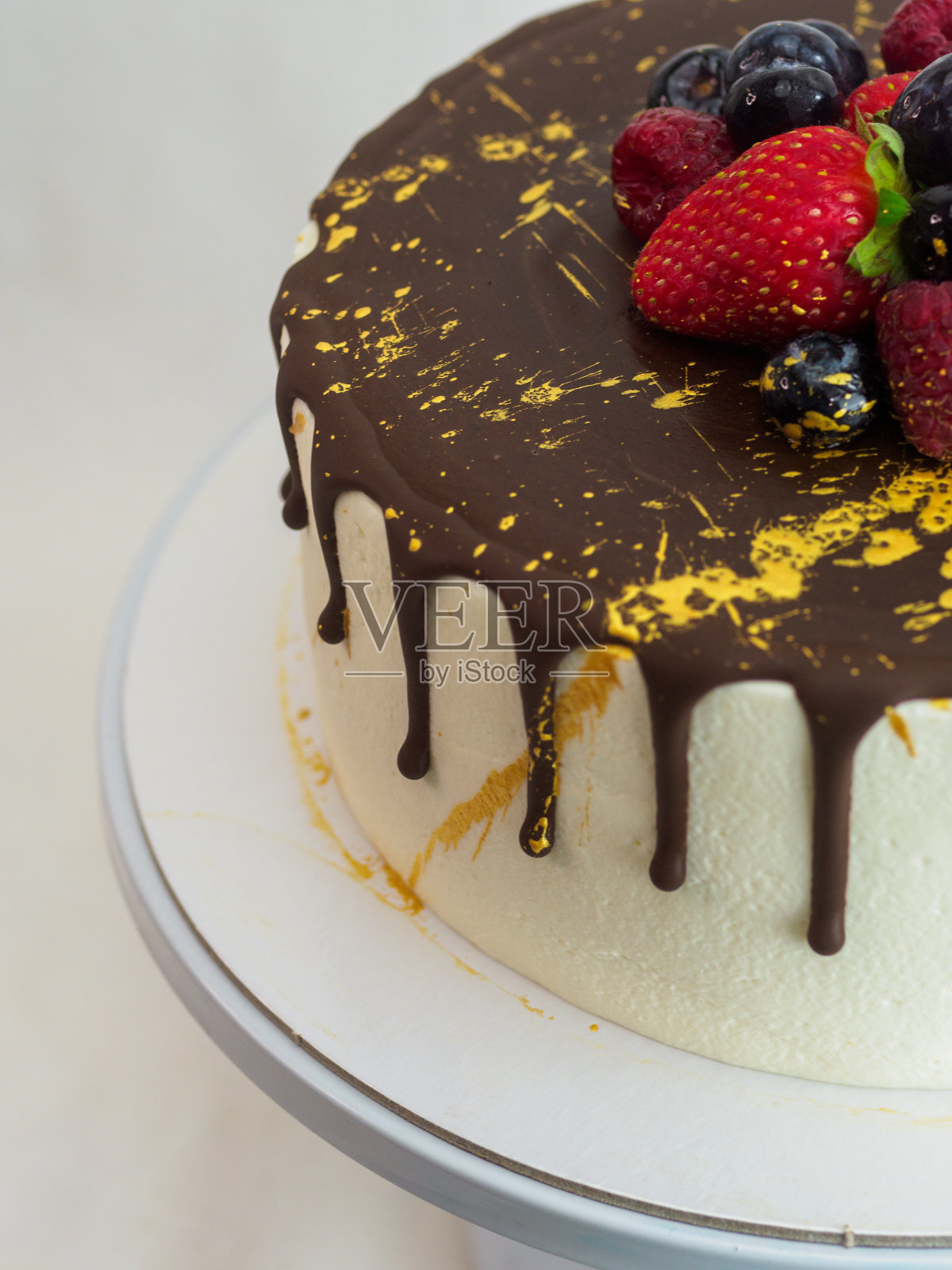 糖霜蛋糕，巧克力覆盖，草莓和蓝莓点缀，金色油漆飞溅照片摄影图片