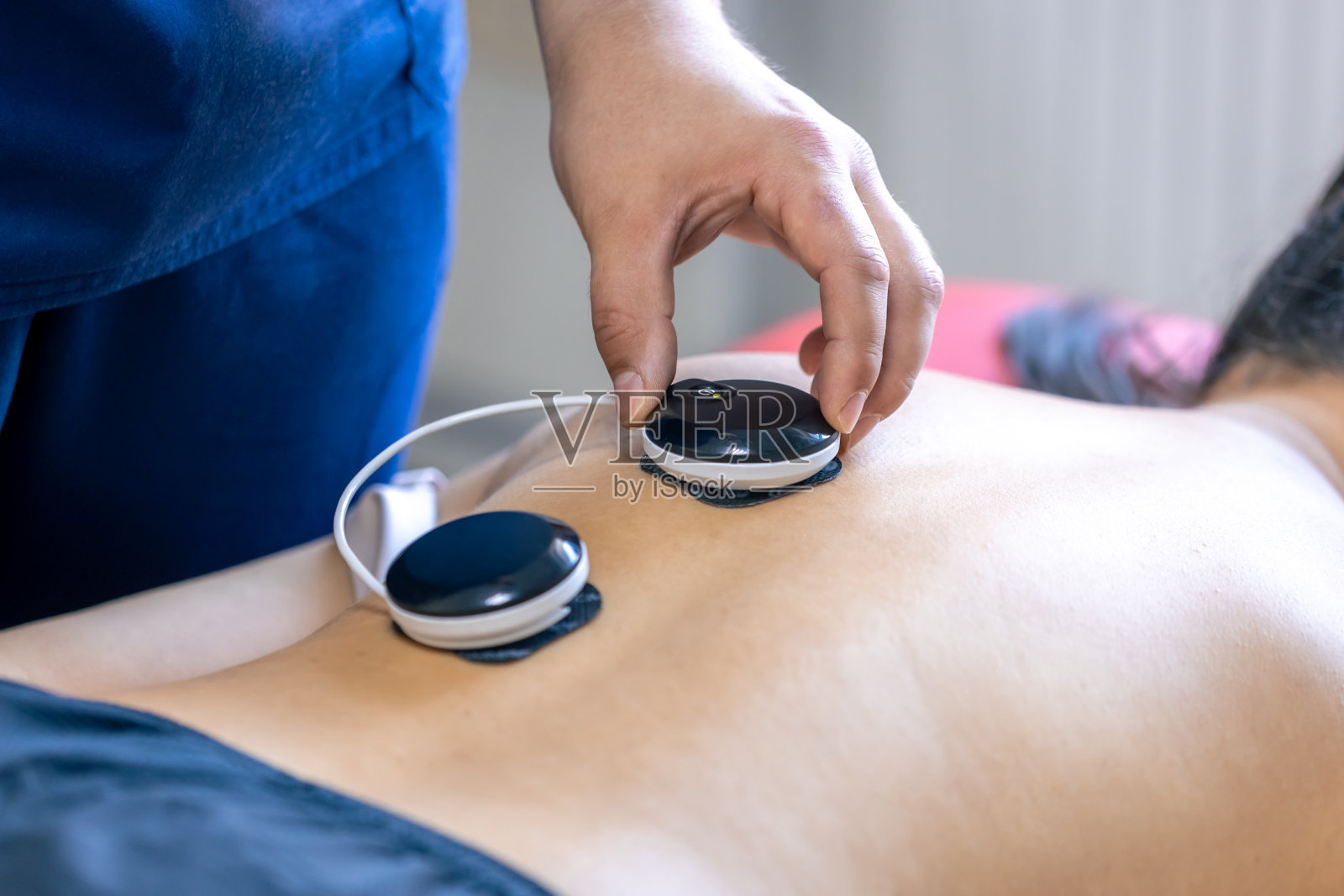 在理疗诊所接受肌刺激治疗的妇女。照片摄影图片