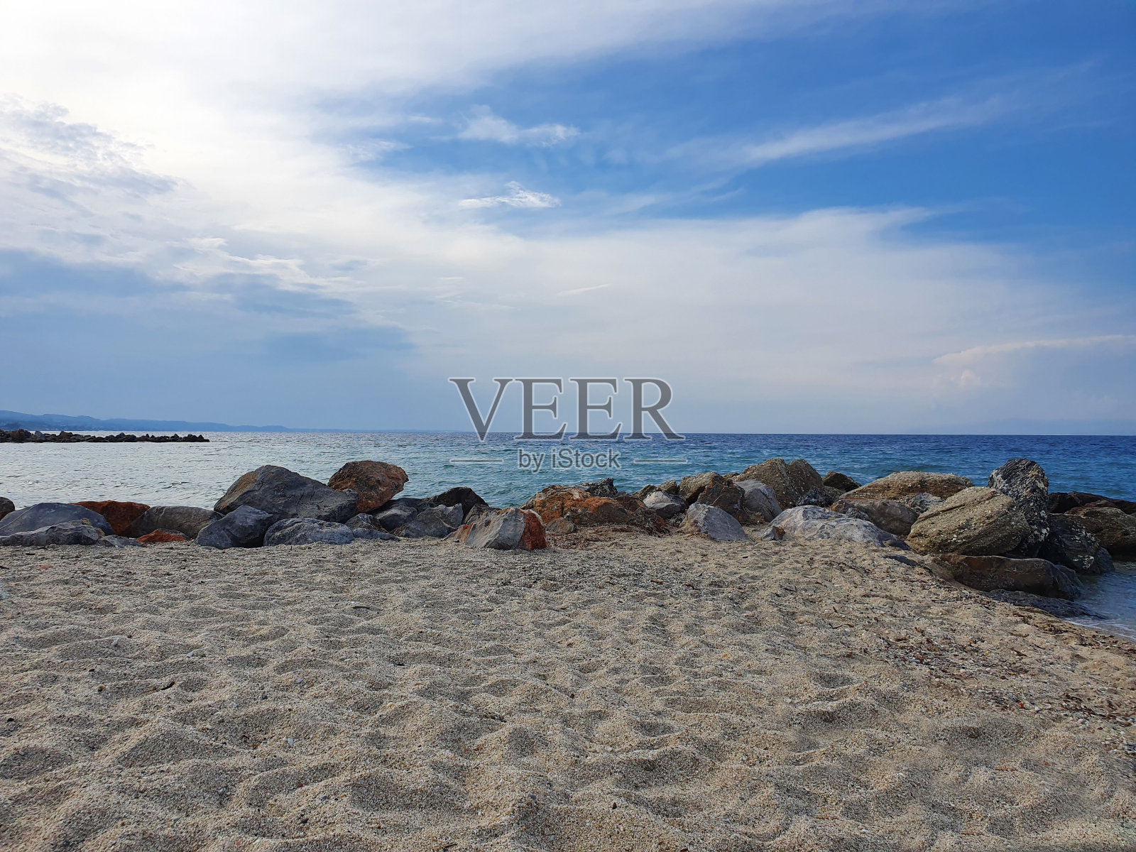 希腊美丽的海滩，鹅卵石和金色的沙滩，还有戏剧性的天空照片摄影图片