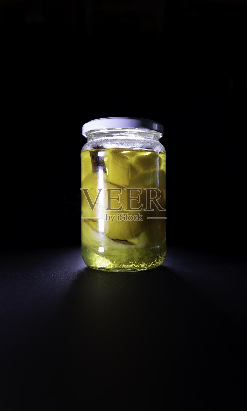 黑色背景上装有柑橘皮和伏特加的玻璃罐。酒精化。罐头的概念照片摄影图片