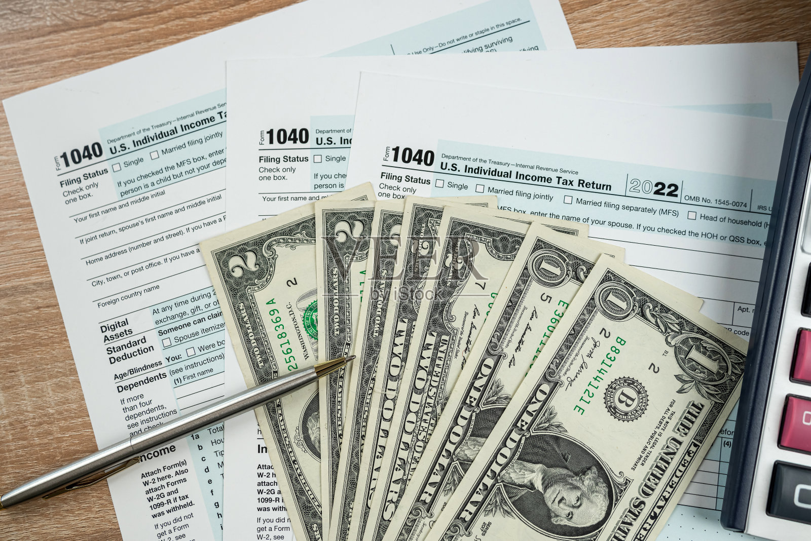 美元钞票和笔躺在1040表格上。提交纳税申报表的概念照片摄影图片