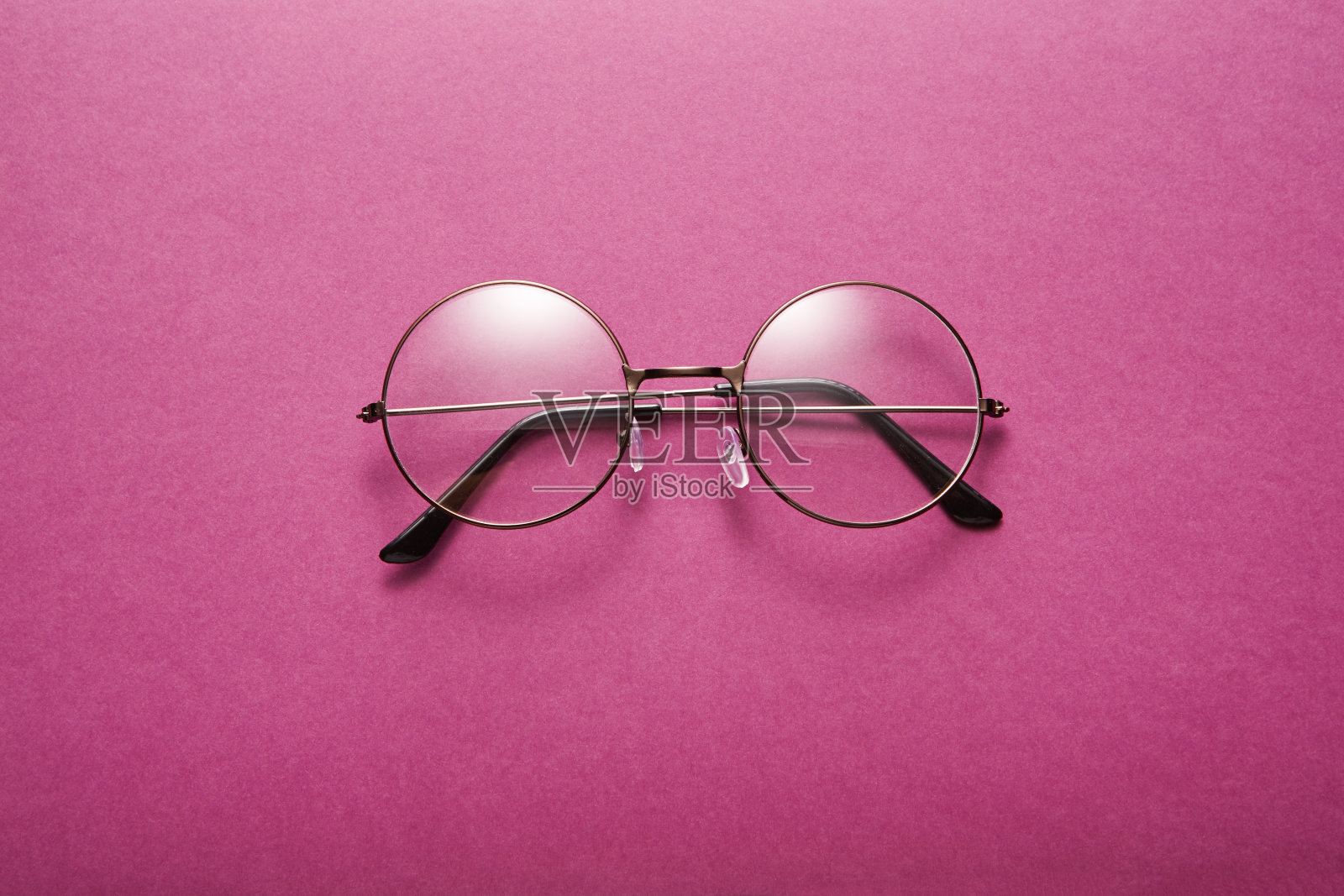 玻璃在圆形薄金属框架隔离在紫色表面。照片摄影图片