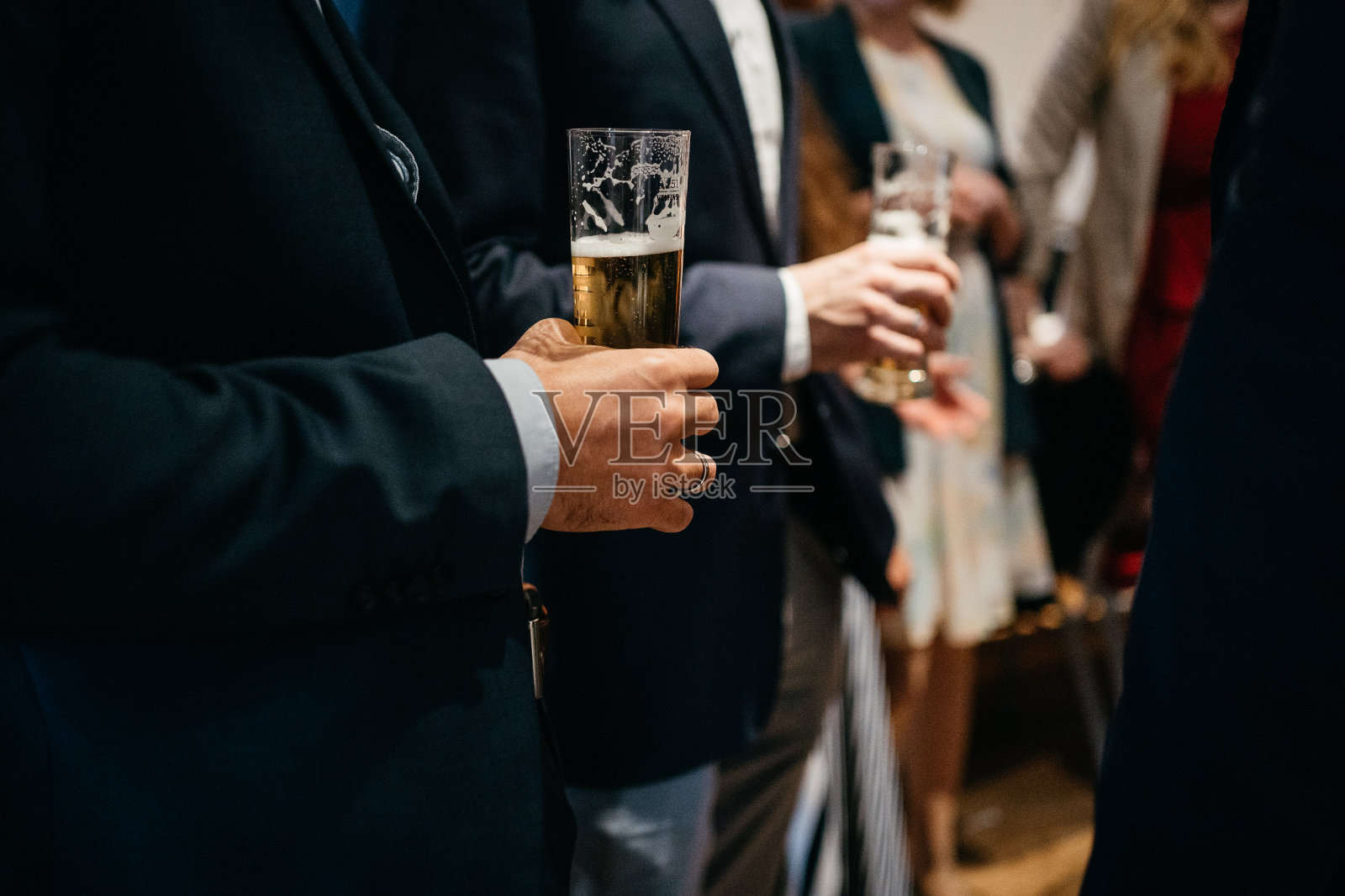 在聚会上，衣冠楚楚的男人拿着啤酒杯照片摄影图片