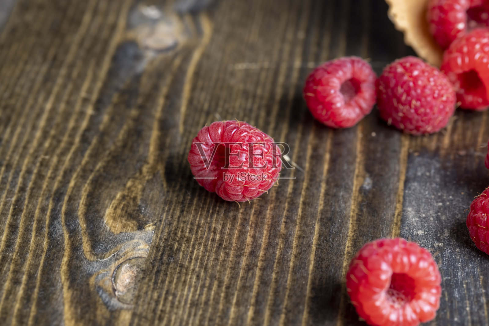 黑色的桌子上放着成熟的红树莓和华夫饼杯照片摄影图片