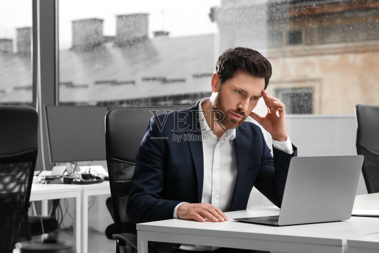 在办公室白色办公桌前用笔记本电脑工作的人照片摄影图片