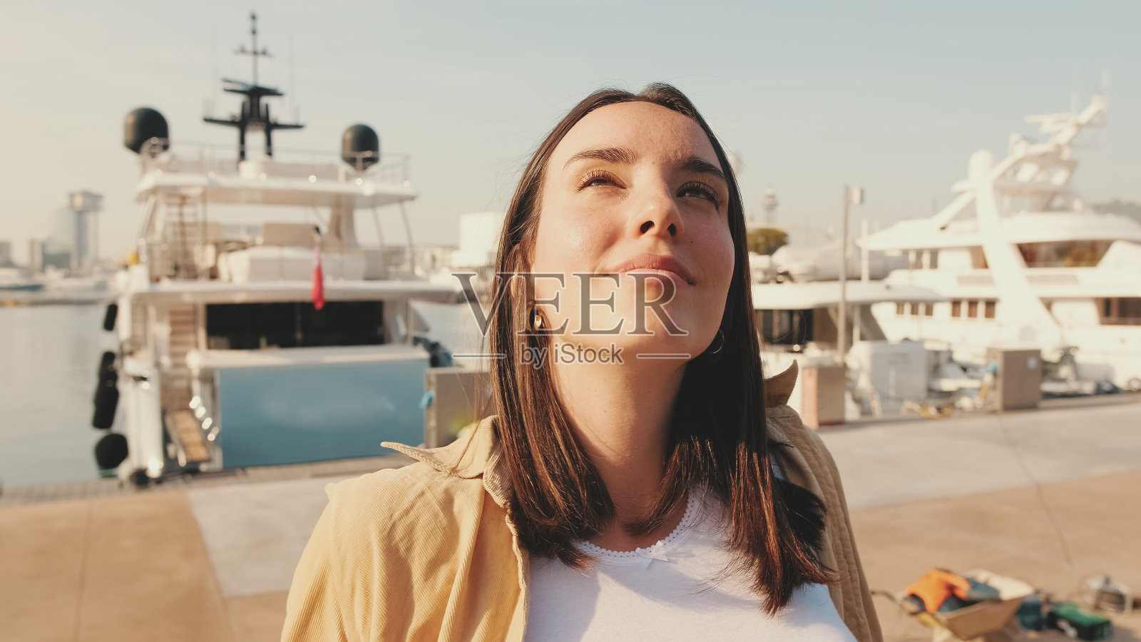 旅行者女孩，坐在欧洲城市的港口享受温暖的阳光照片摄影图片