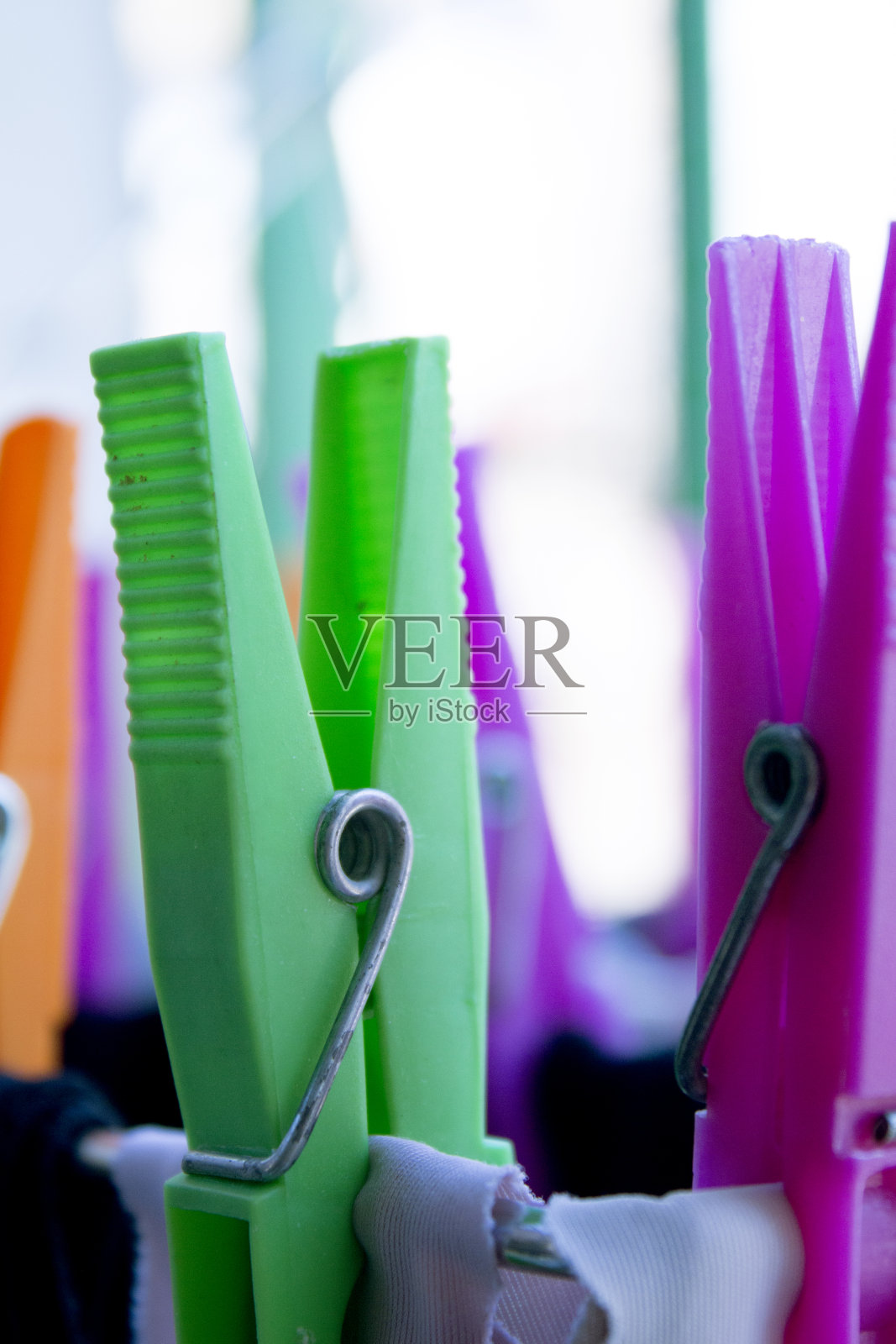 把衣服固定在晒衣绳上的衣夹。各种各样的颜色。照片摄影图片