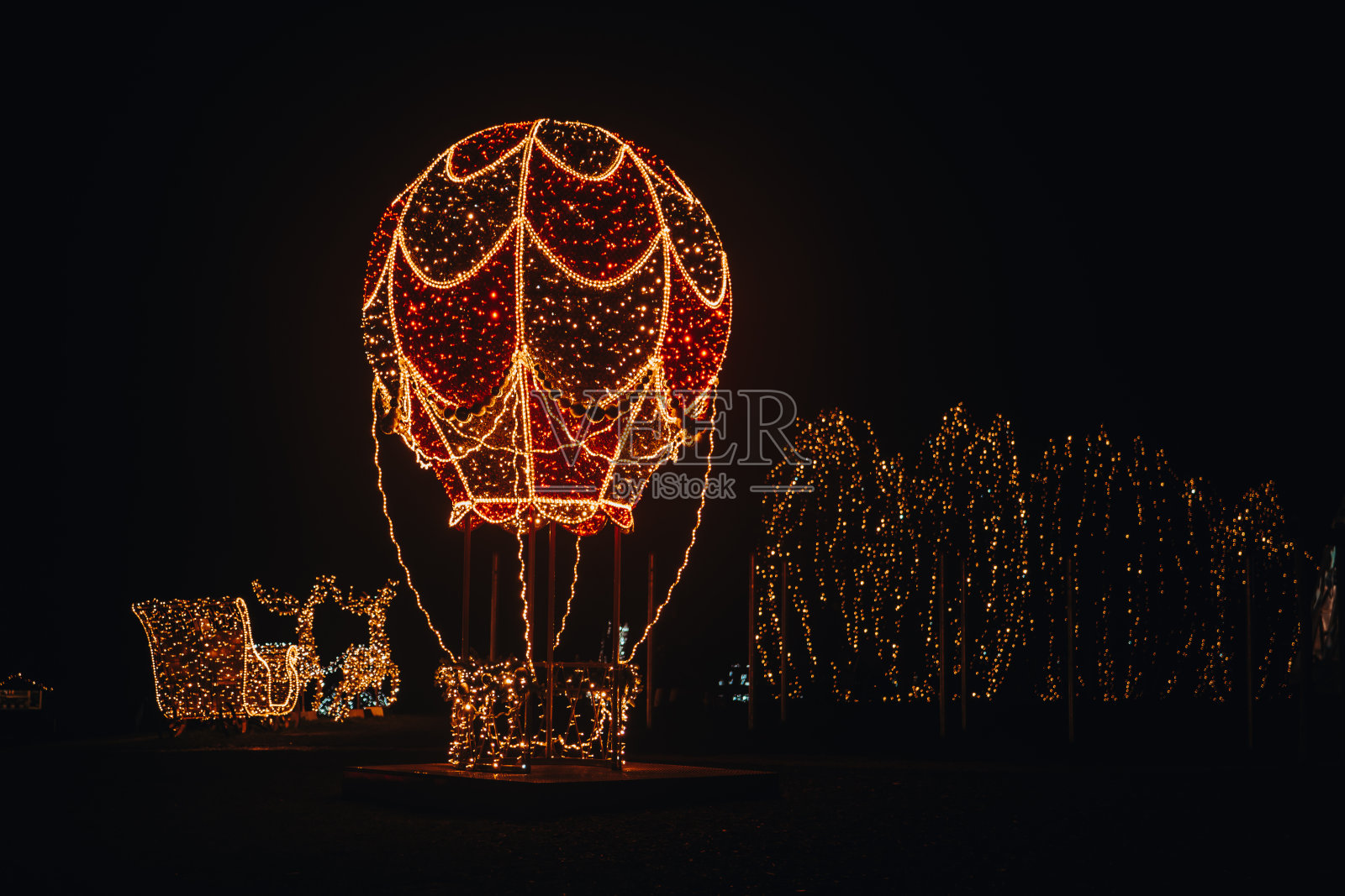 黑暗中闪闪发光的身影。圣诞街上安装闪亮的花环。发光的气球，用花环做雪橇的驯鹿。喜庆的圣诞街道装饰照片摄影图片