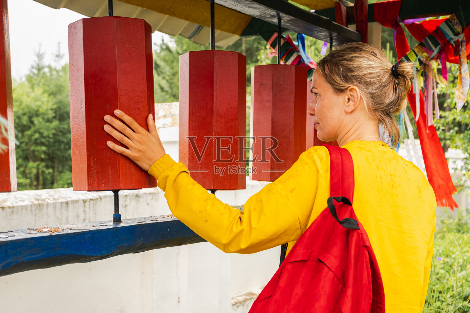 一名女朝圣者在佛教寺院触摸旋转佛经轮。佛塔寺庙里的经轮。佛教的宗教观念。照片摄影图片