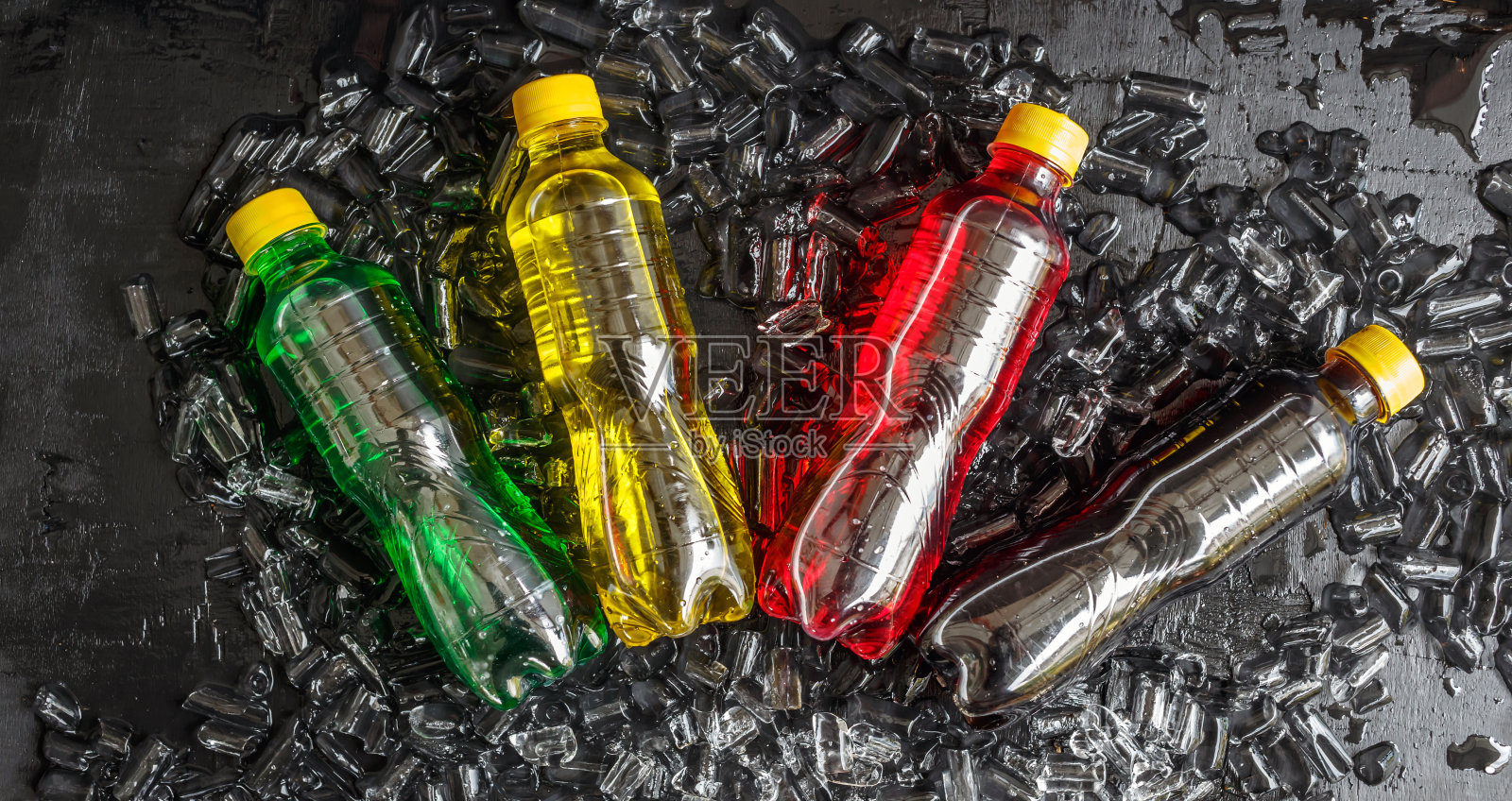 俯视图很多瓶子的软饮料在彩色冰上冷冻的味道在冰块的背景，软饮料瓶或碳酸饮料在黑色的背景照片摄影图片