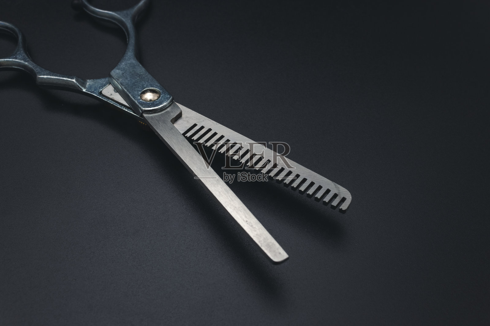 黑色背景的理发剪刀。时尚的专业理发师剪刀。工具保养，剪刀锐化照片摄影图片