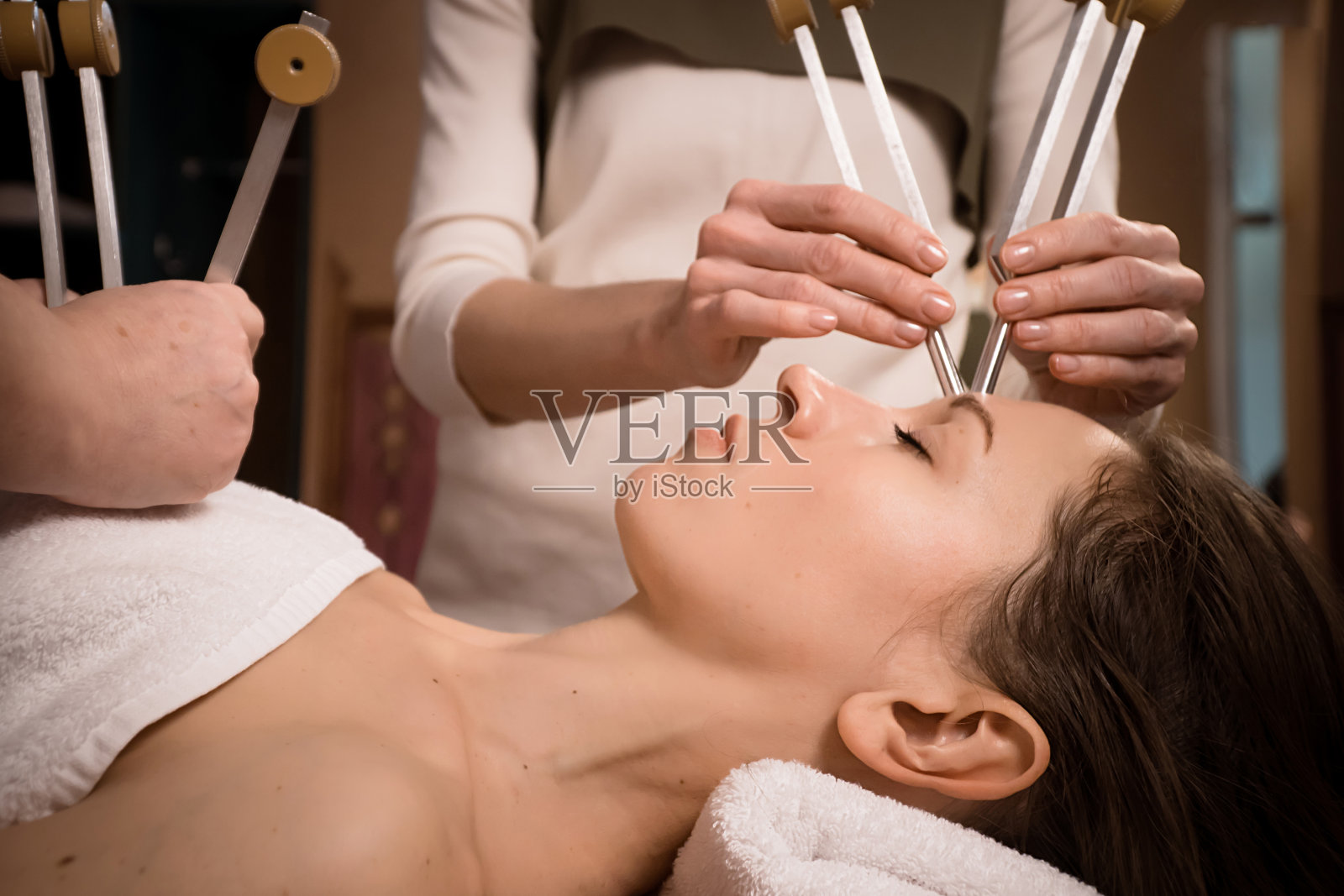 女人在水疗中心放松，用音叉进行声音按摩照片摄影图片